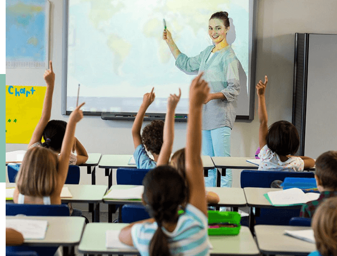 A group of children in class raising their hands.