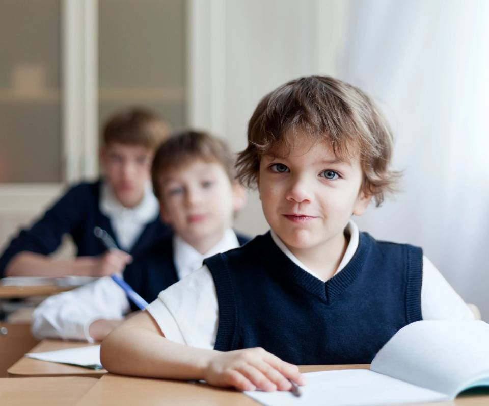 A group of children sitting at a table with papers.